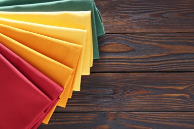 Different colorful napkins on wooden table, top view. Space for text