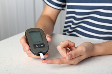 Photo of Woman checking blood sugar level with glucometer at table. Diabetes test