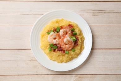 Plate with fresh tasty shrimps, bacon, grits and green onion on light wooden table, top view