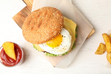 Photo of Tasty burger with fried egg on wooden background, flat lay