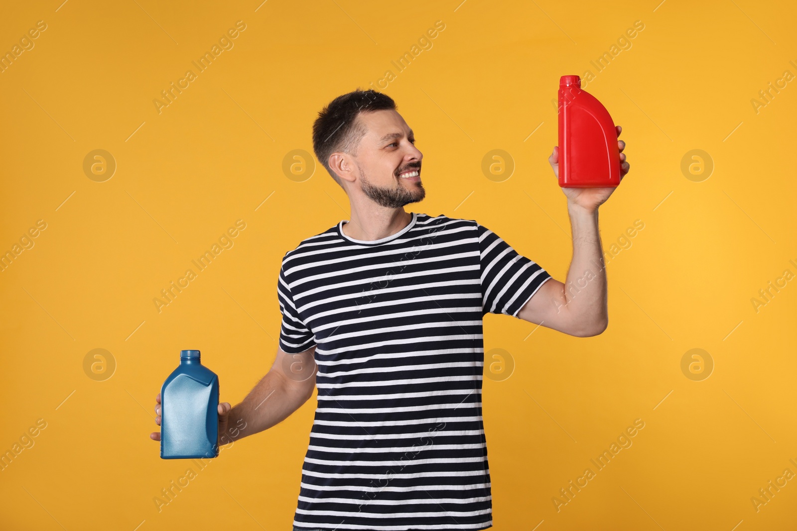 Photo of Man holding two containers of motor oil on orange background