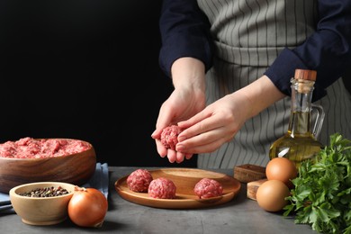 Photo of Woman making meatball from ground meat at grey table, closeup