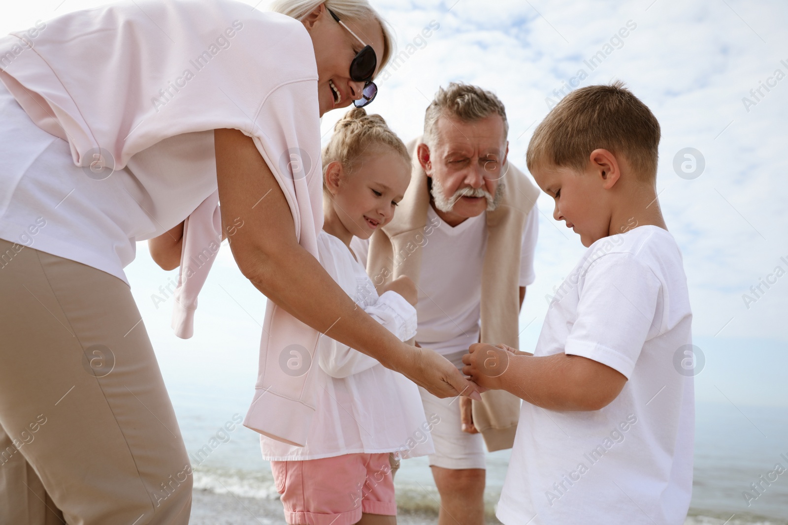 Photo of Cute little children with grandparents on sea beach