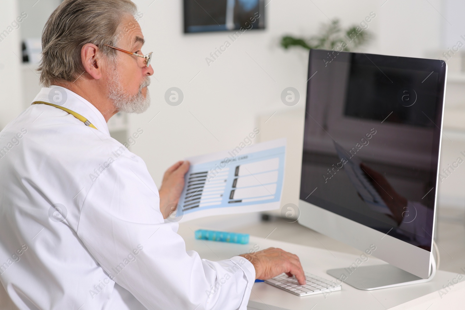 Photo of Doctor with patient's medical card at table in clinic