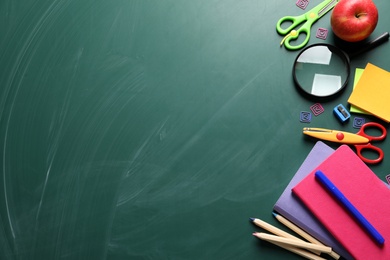 Flat lay composition with scissors and school supplies on chalkboard. Space for text