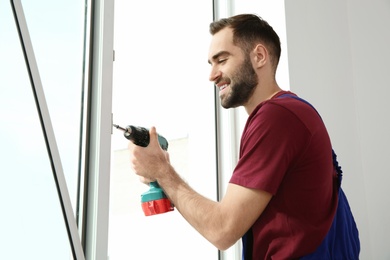 Construction worker using drill while installing window indoors