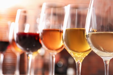 Different tasty wines in glasses against blurred background