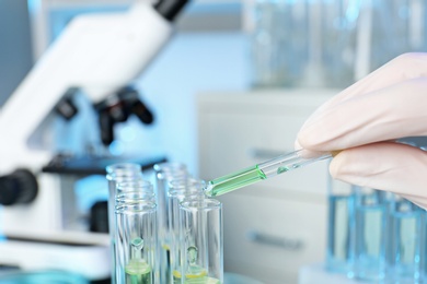 Photo of Analyst dripping reagent into test tube with sample at laboratory, closeup. Chemical analysis