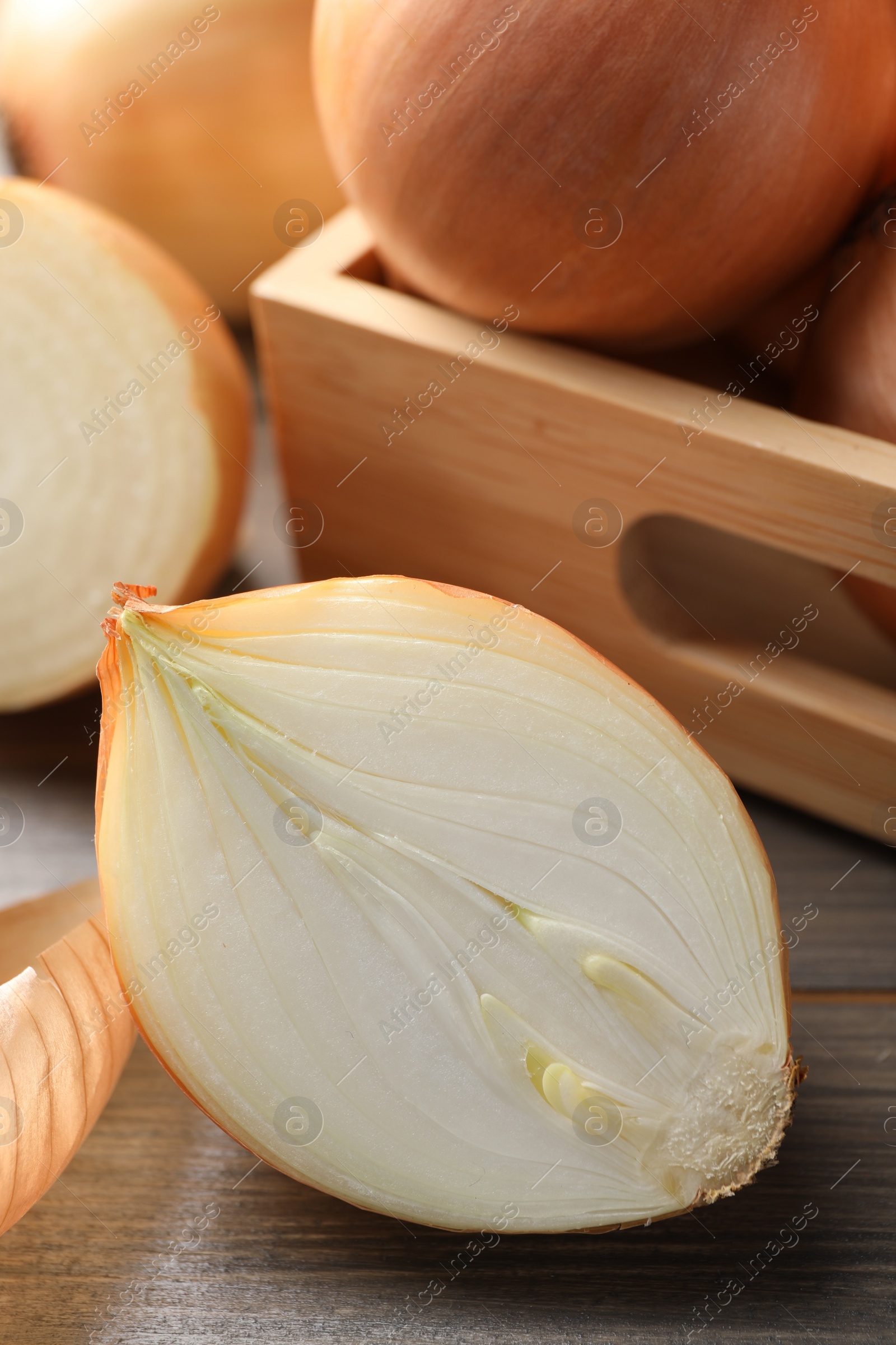 Photo of Whole and cut onions on wooden table, closeup