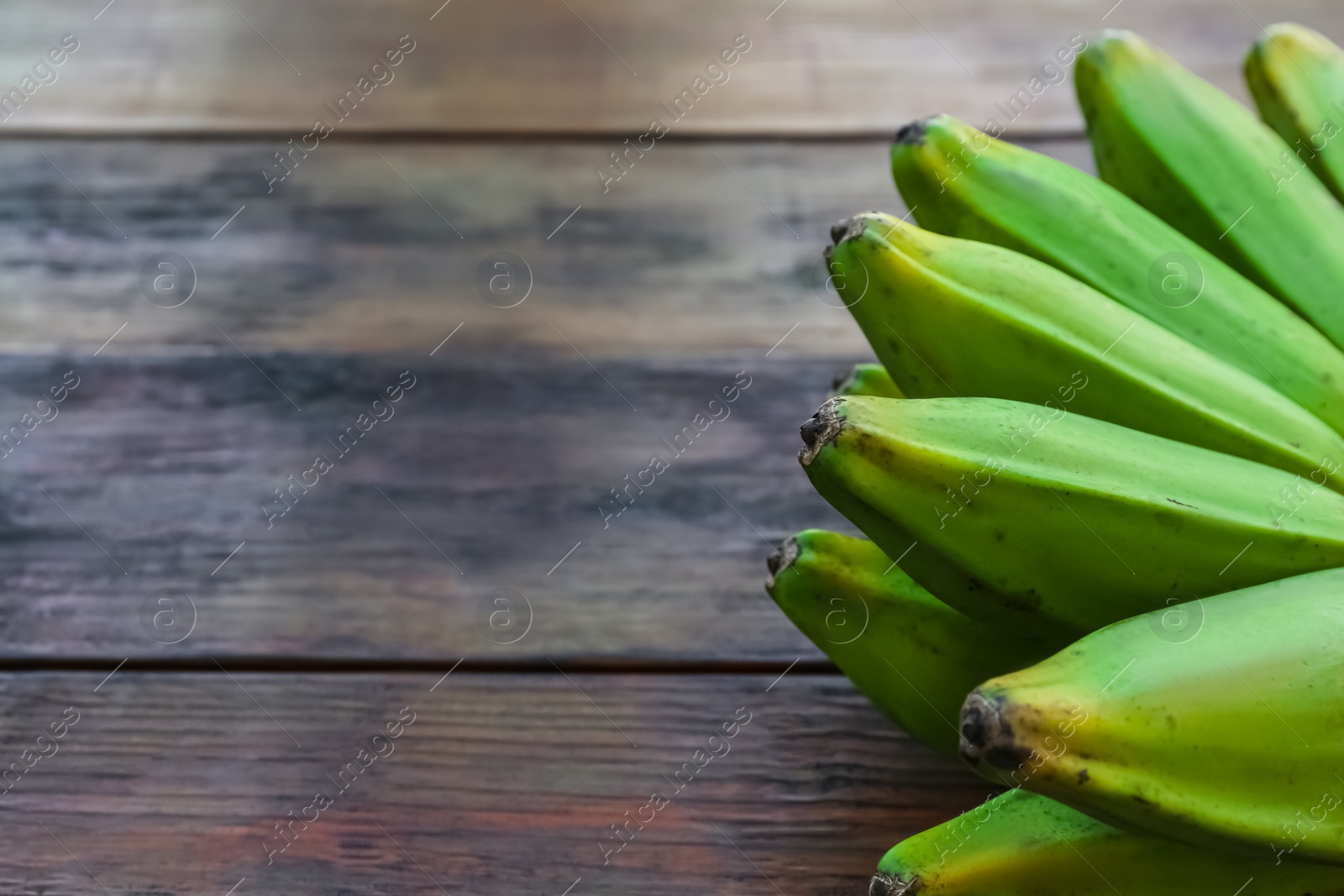 Photo of Bunch of delicious bananas on wooden table, closeup. Space for text