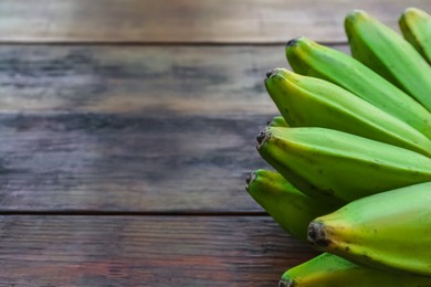 Bunch of delicious bananas on wooden table, closeup. Space for text