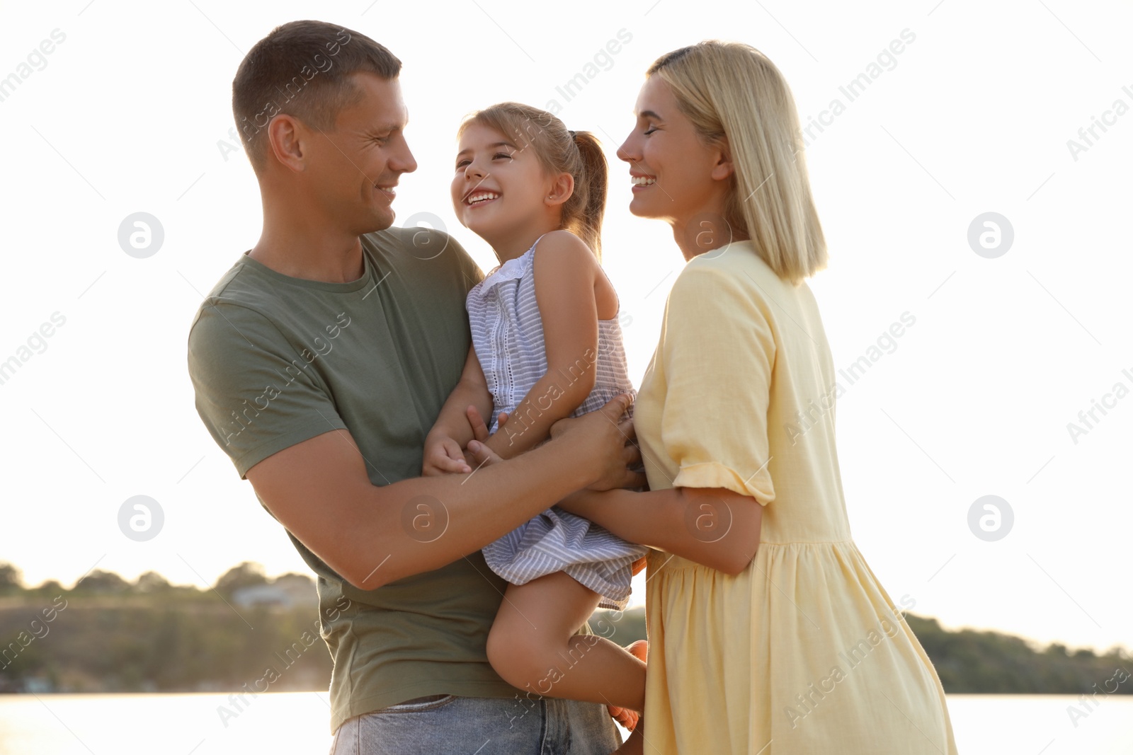 Photo of Happy parents with their child on beach. Spending time in nature