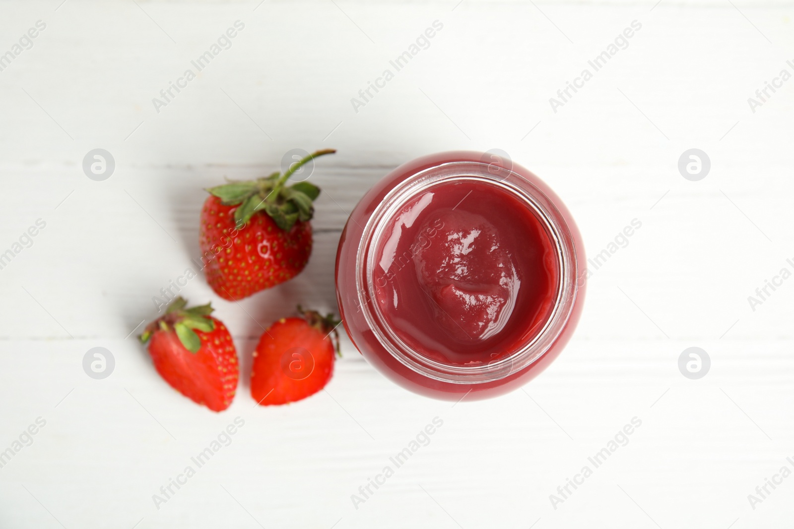 Photo of Healthy baby food in jar and fresh strawberries on white wooden table, top view