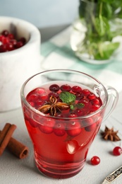 Photo of Tasty hot cranberry tea with mint and fresh ingredients on light table