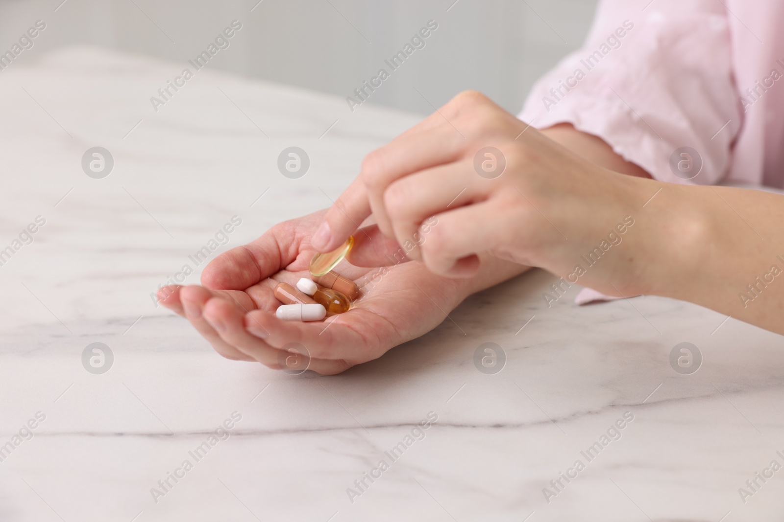 Photo of Woman with vitamin pills at table indoors, closeup