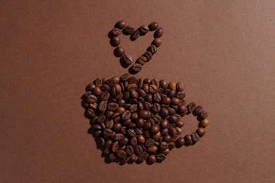 Photo of Cup of hot drink, composition made with coffee beans on brown background, flat lay