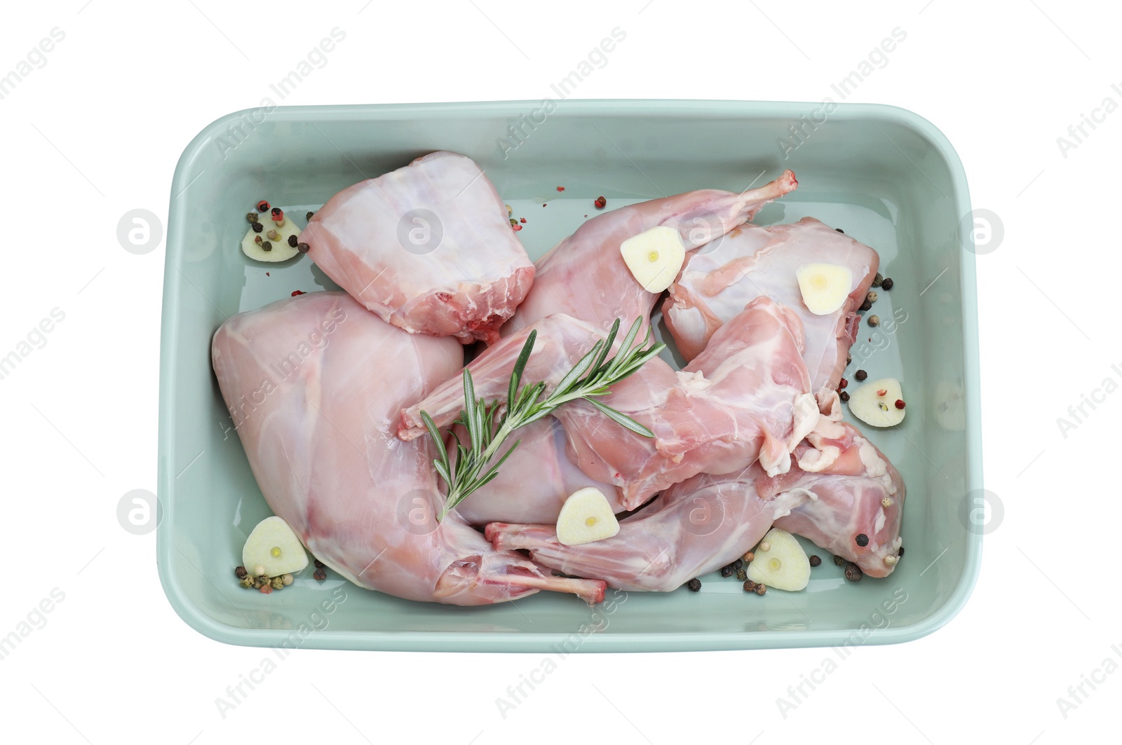 Photo of Raw rabbit meat, spices and garlic in baking dish isolated on white, top view