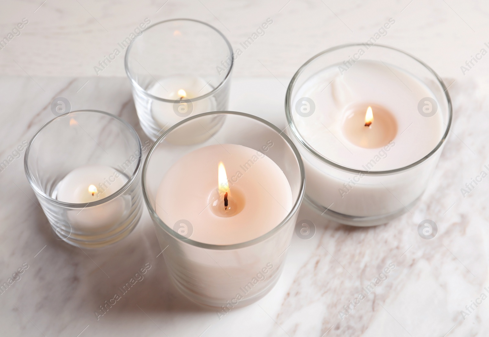 Photo of Burning candles in glasses on marble table