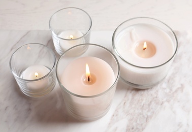 Photo of Burning candles in glasses on marble table
