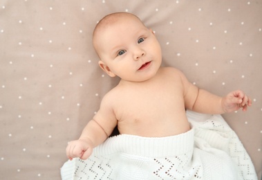 Adorable baby girl lying in bed, top view