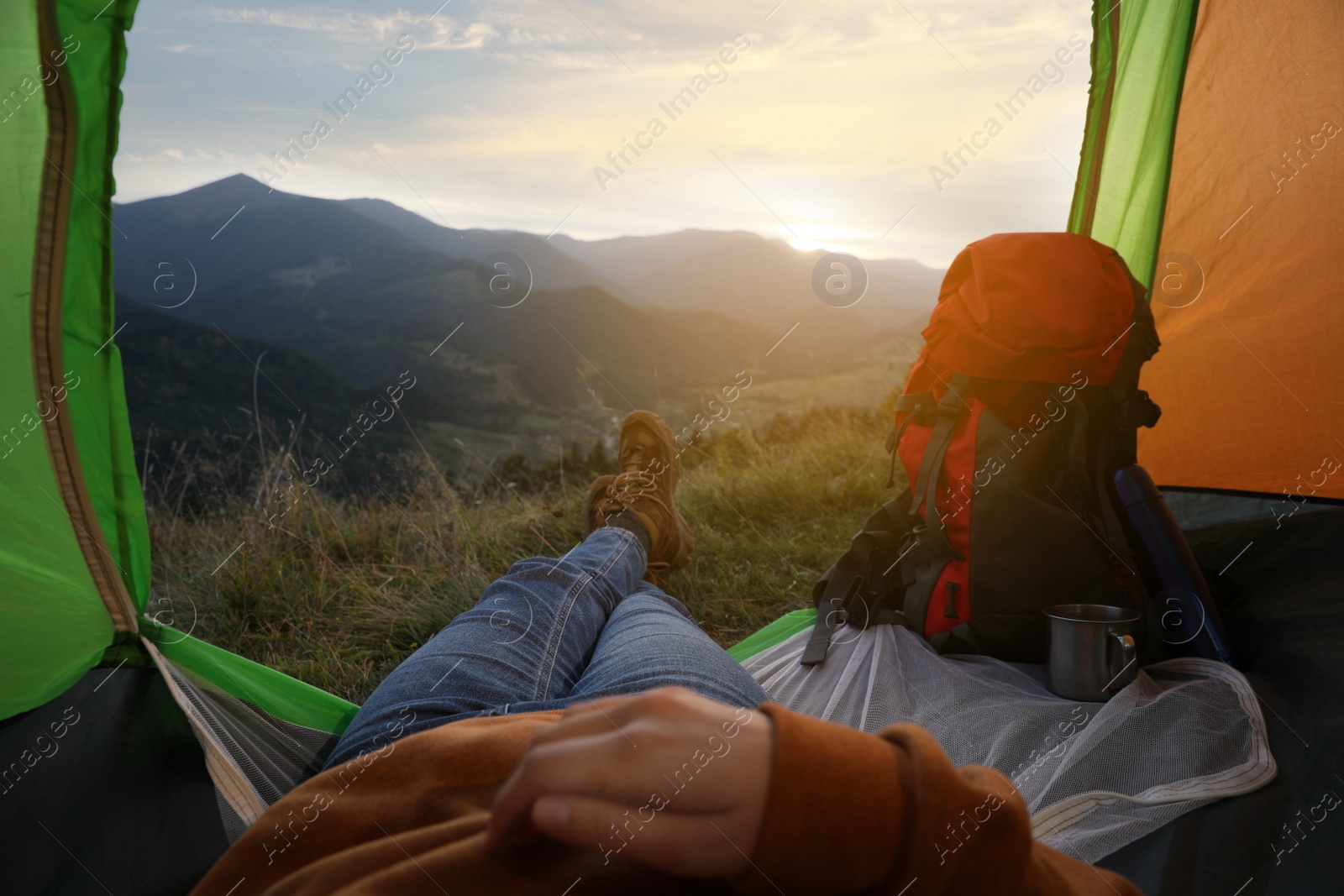 Photo of Woman resting inside of camping tent in mountains at sunset, closeup