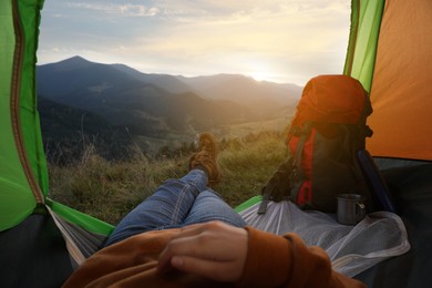 Woman resting inside of camping tent in mountains at sunset, closeup