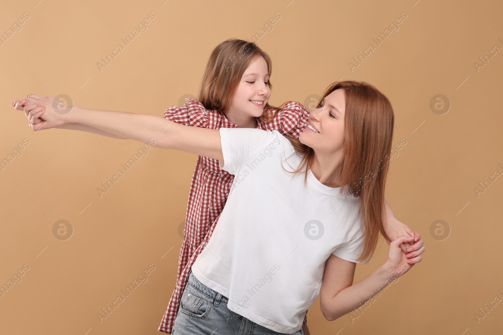 Photo of Happy mother with her cute daughter on beige background