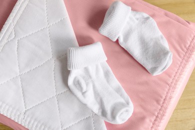 Soft blanket and baby socks on wooden table, closeup