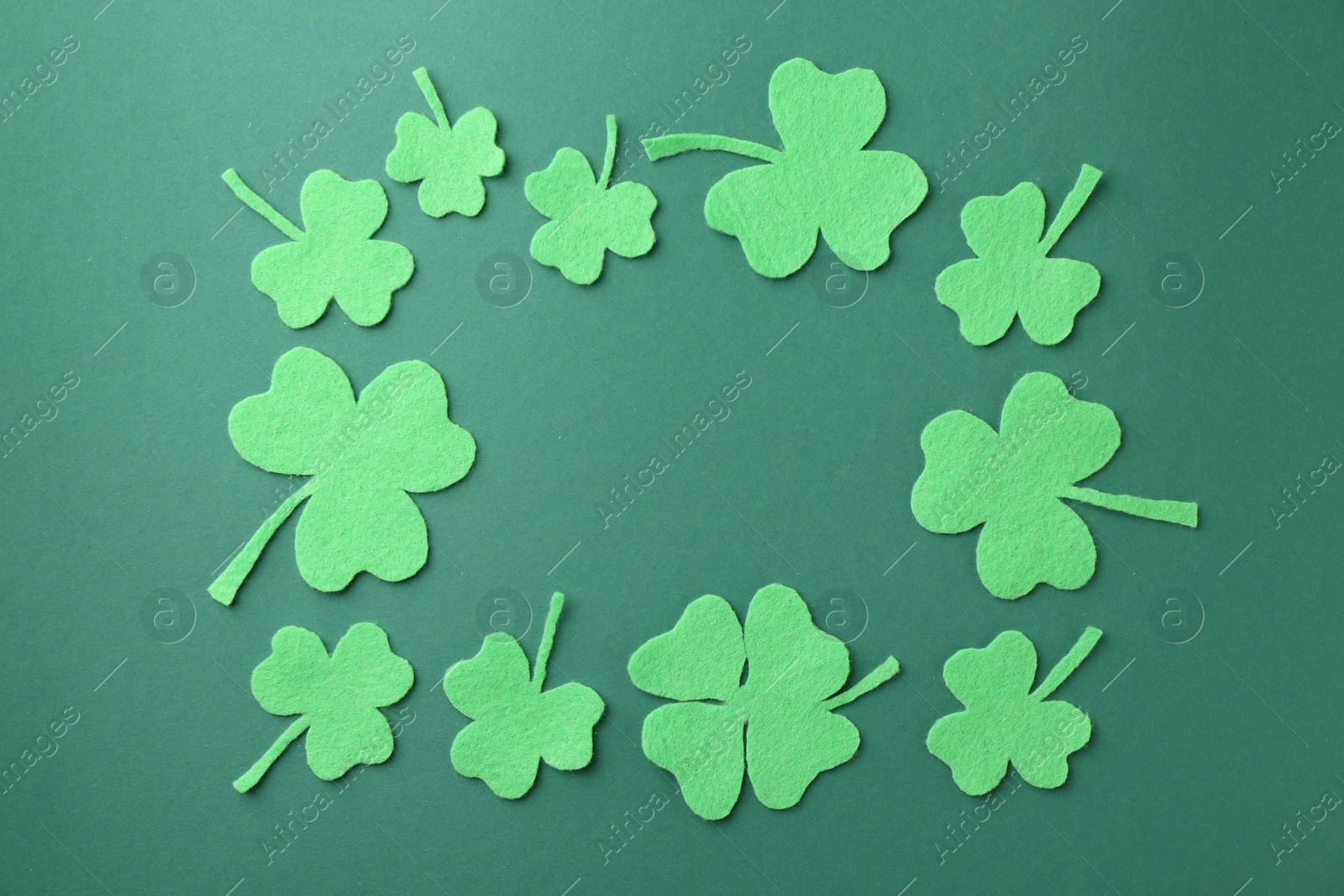 Photo of St. Patrick's day. Frame of decorative clover leaves on green background, flat lay. Space for text