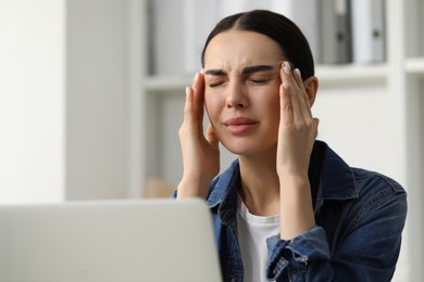 Photo of Woman suffering from headache at workplace in office, space for text