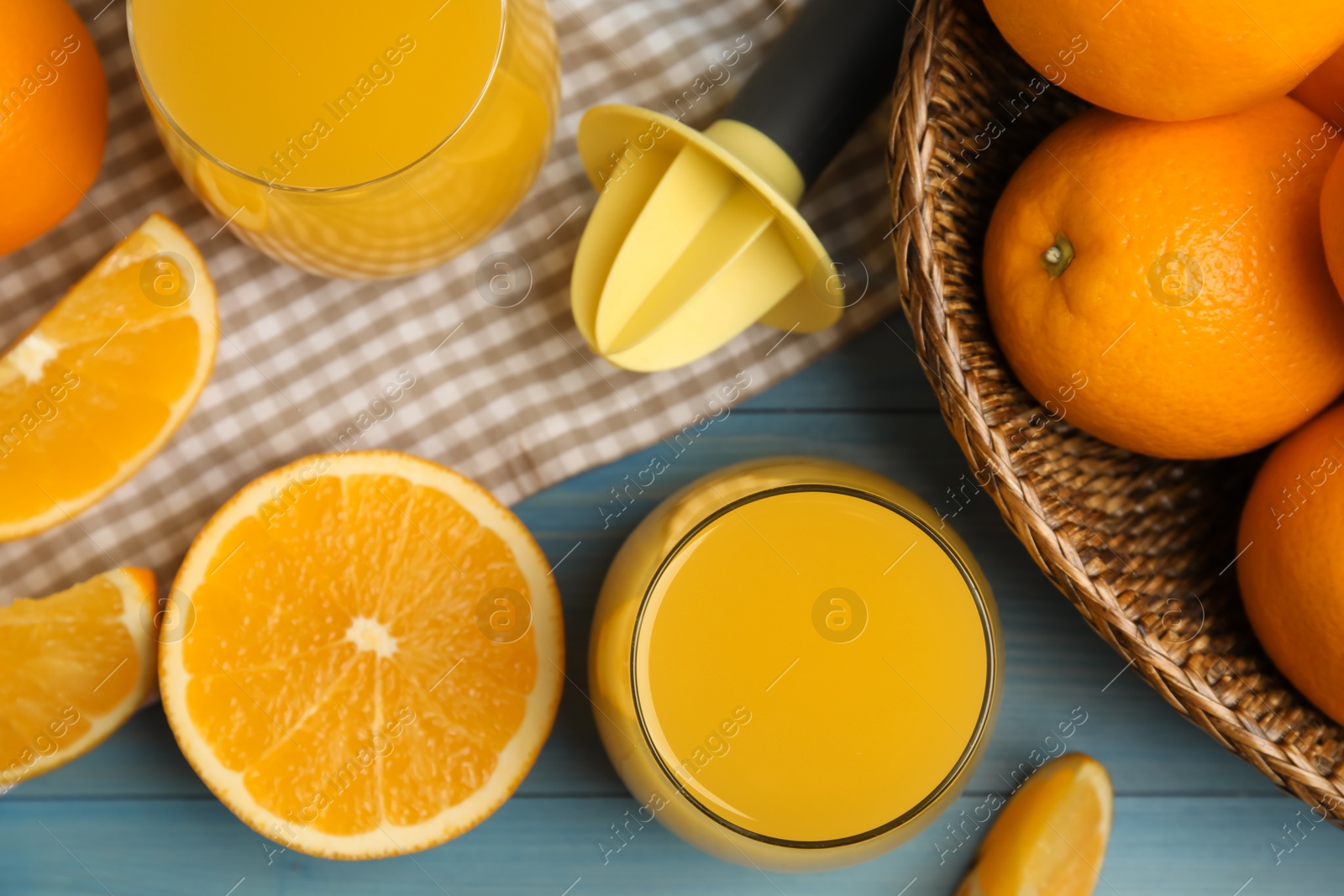 Photo of Freshly made juice, oranges and reamer on blue wooden table, flat lay