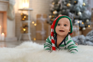 Photo of Little baby wearing elf hat on floor at home. First Christmas
