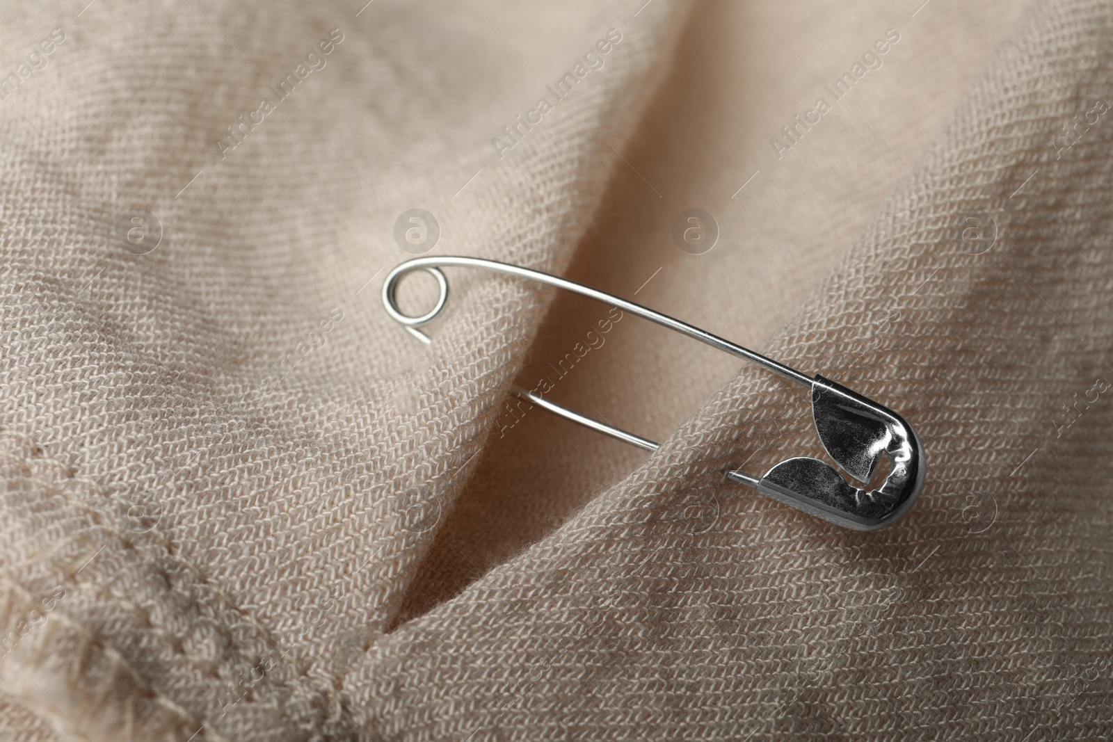 Photo of Closeup view of metal safety pin on clothing