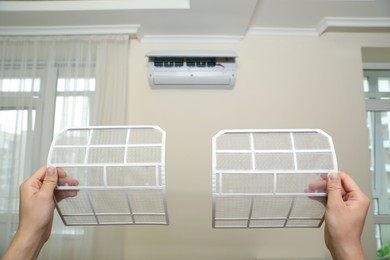 Photo of Man holding filters of air conditioner at home, closeup