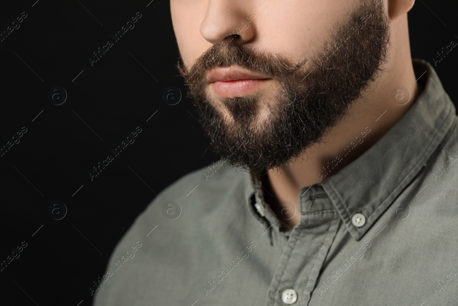 Photo of Handsome young man with mustache on black background, closeup