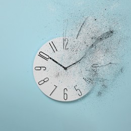 Image of Flow of time. Analog clock dissolving on light blue background