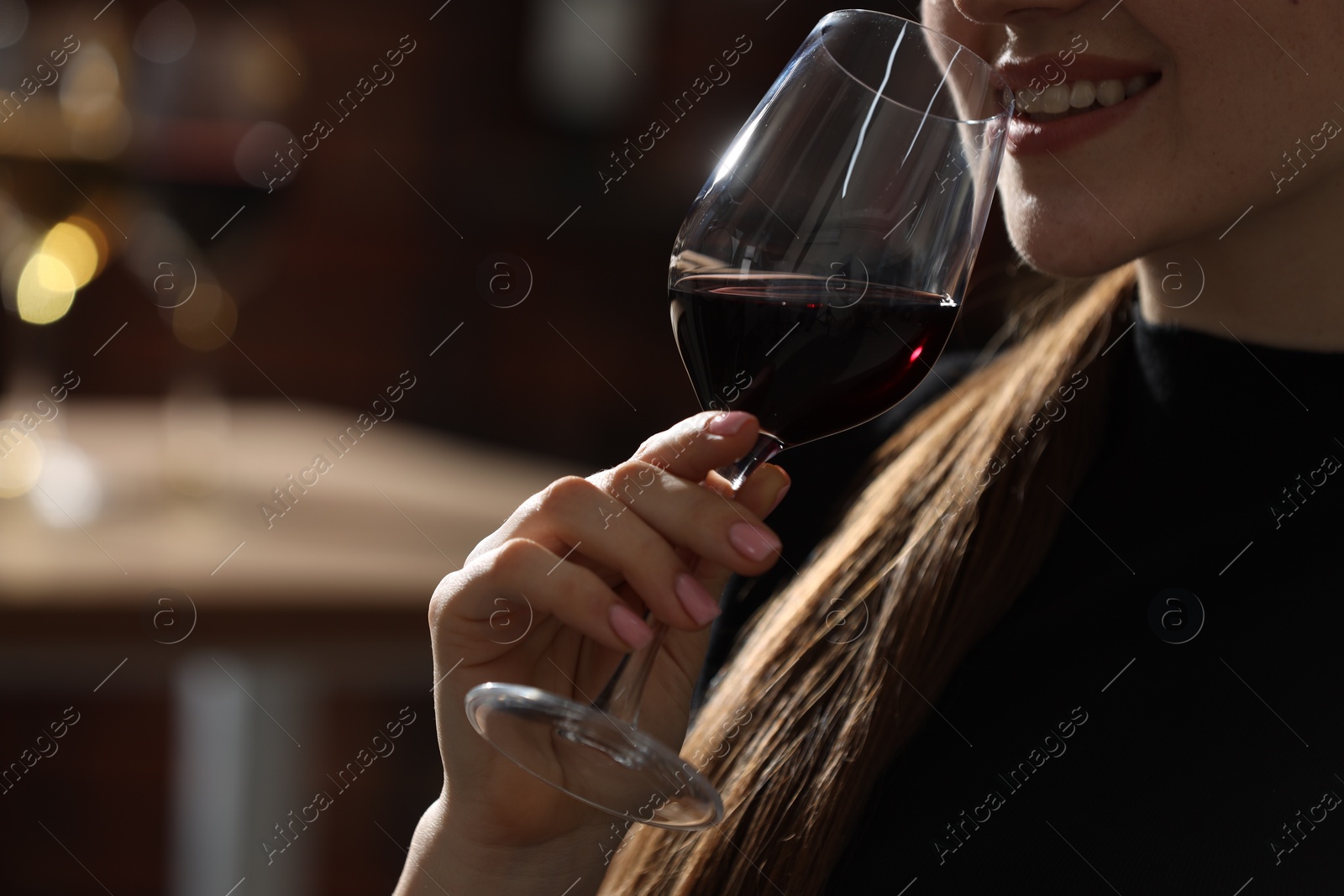 Photo of Woman with glass of red wine against blurred background, closeup. Space for text