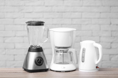 Photo of Kitchen appliances on table against brick wall background. Interior element