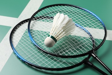 Photo of Feather badminton shuttlecock and rackets on green table, closeup