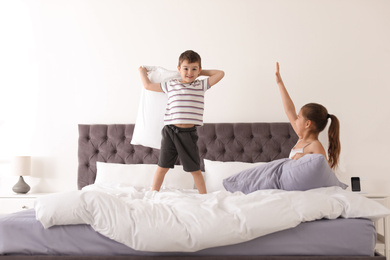 Happy children having pillow fight in bedroom