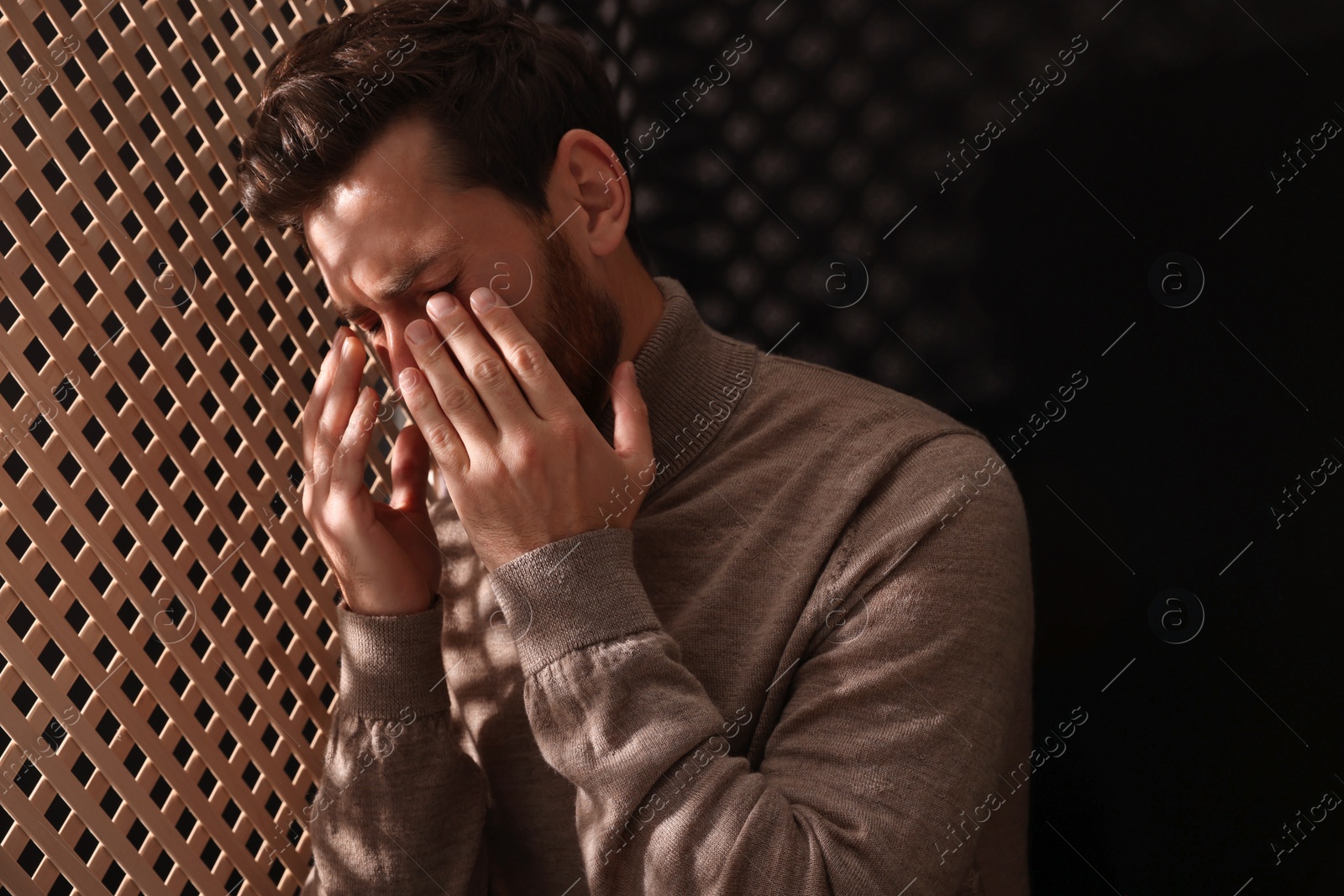 Photo of Upset man listening to priest during confession in booth, space for text