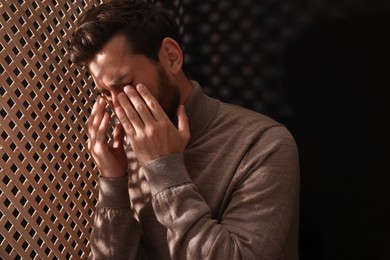 Photo of Upset man listening to priest during confession in booth, space for text