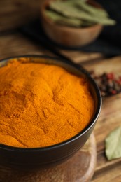 Aromatic saffron powder in bowl on wooden table, closeup