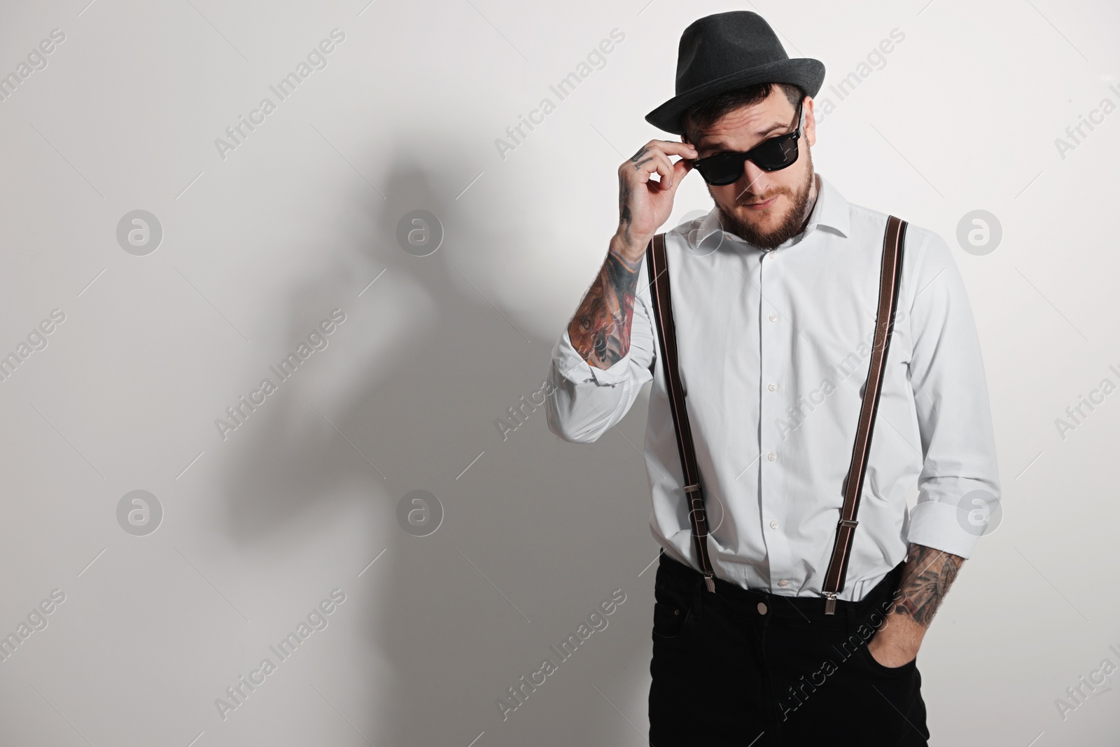 Photo of Handsome hipster man wearing stylish sunglasses on light grey background. Space for text