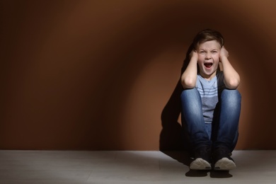 Photo of Depressed little boy sitting on floor indoors. Time to visit child psychologist