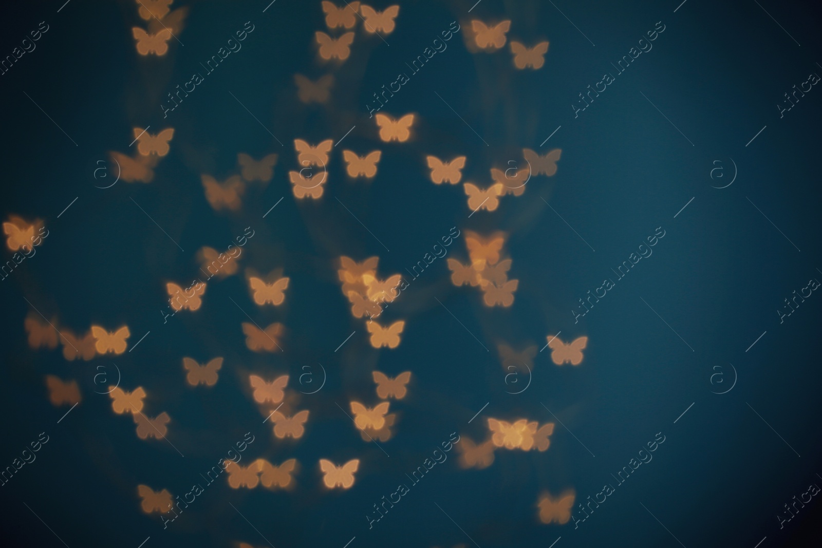 Photo of Blurred view of beautiful butterfly shaped lights on blue background. Bokeh effect