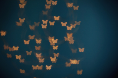 Photo of Blurred view of beautiful butterfly shaped lights on blue background. Bokeh effect