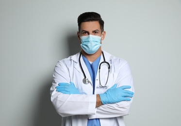 Photo of Doctor in protective mask and medical gloves against light grey background
