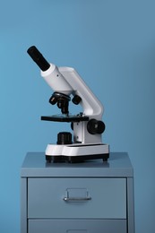 Microscope on laboratory cabinet against blue background