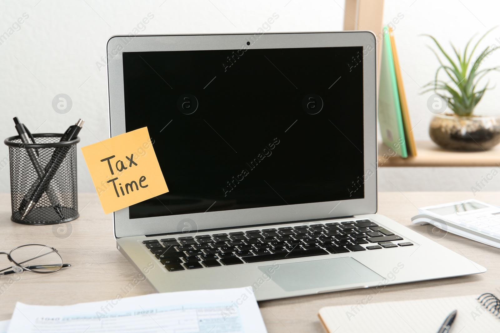 Photo of Reminder note with words Tax Time and laptop on wooden table indoors
